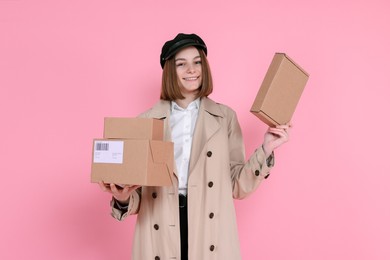 Photo of Happy postwoman with parcels on pink background