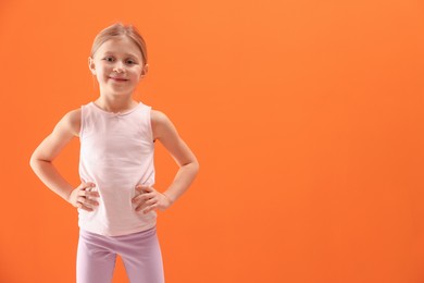 Photo of Little girl in sportswear on orange background, space for text