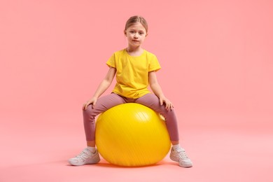 Photo of Cute little girl with fitness ball on pink background