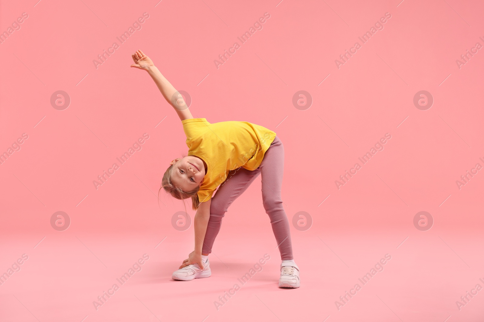 Photo of Cute little girl exercising on pink background