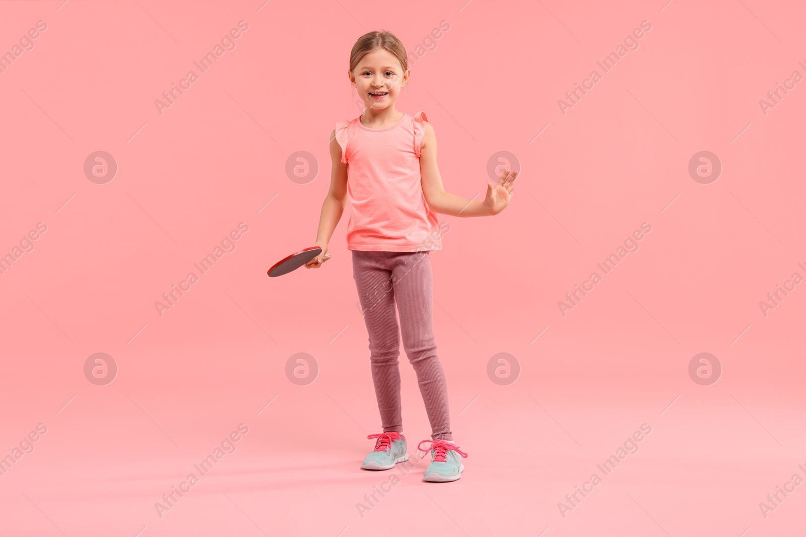 Photo of Cute little girl with ping pong racket on pink background