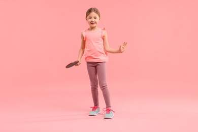 Photo of Cute little girl with ping pong racket on pink background