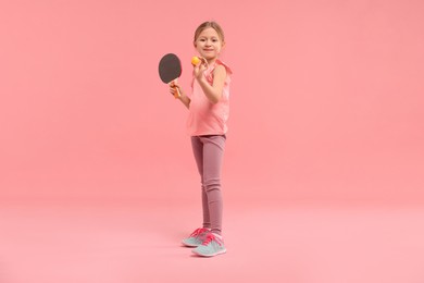 Photo of Cute little girl with ping pong racket and ball on pink background