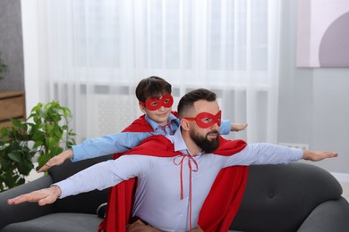 Photo of Father and his son wearing superhero costumes at home