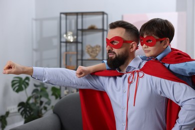 Photo of Father and his son wearing superhero costumes at home