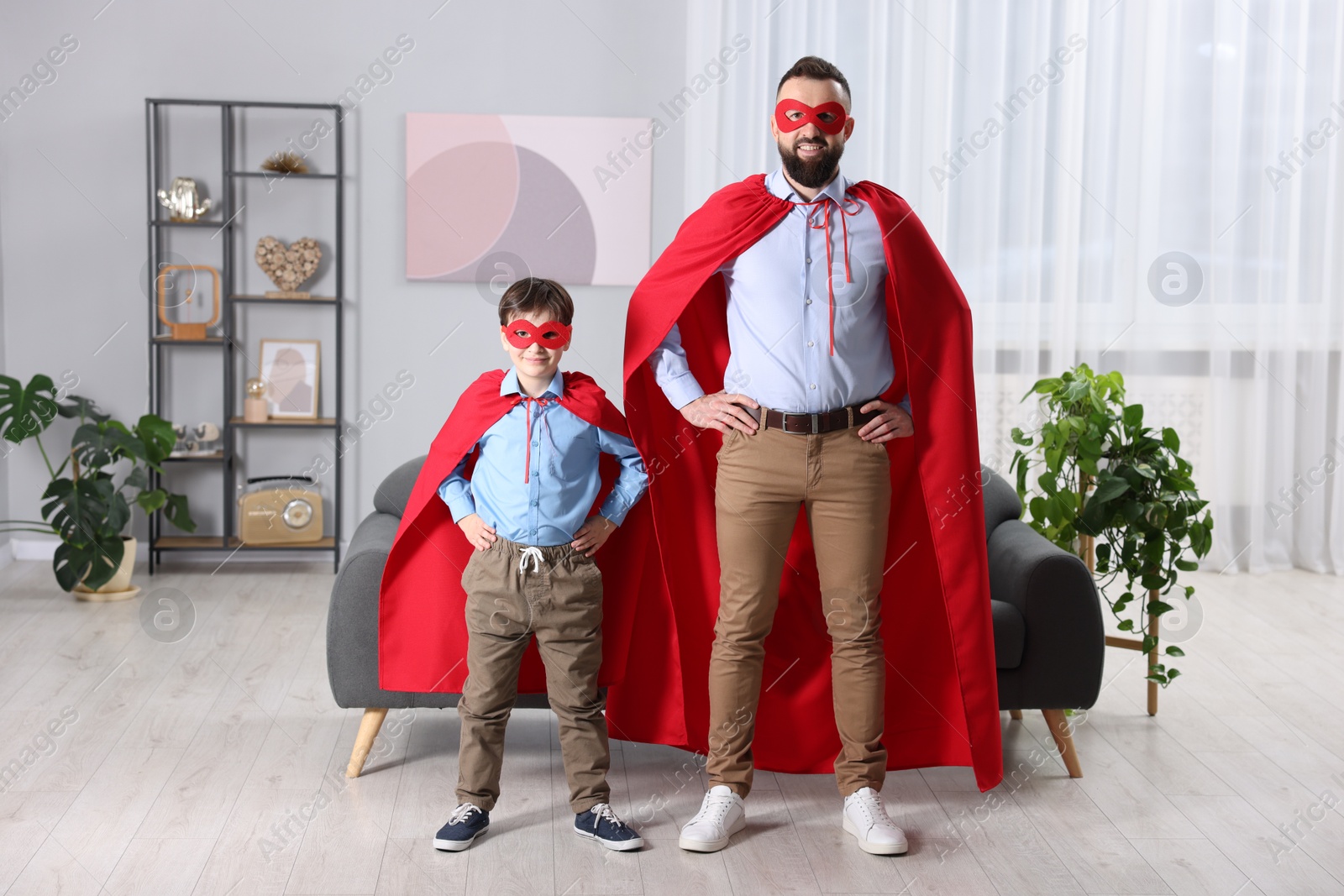 Photo of Father and his son wearing superhero costumes at home