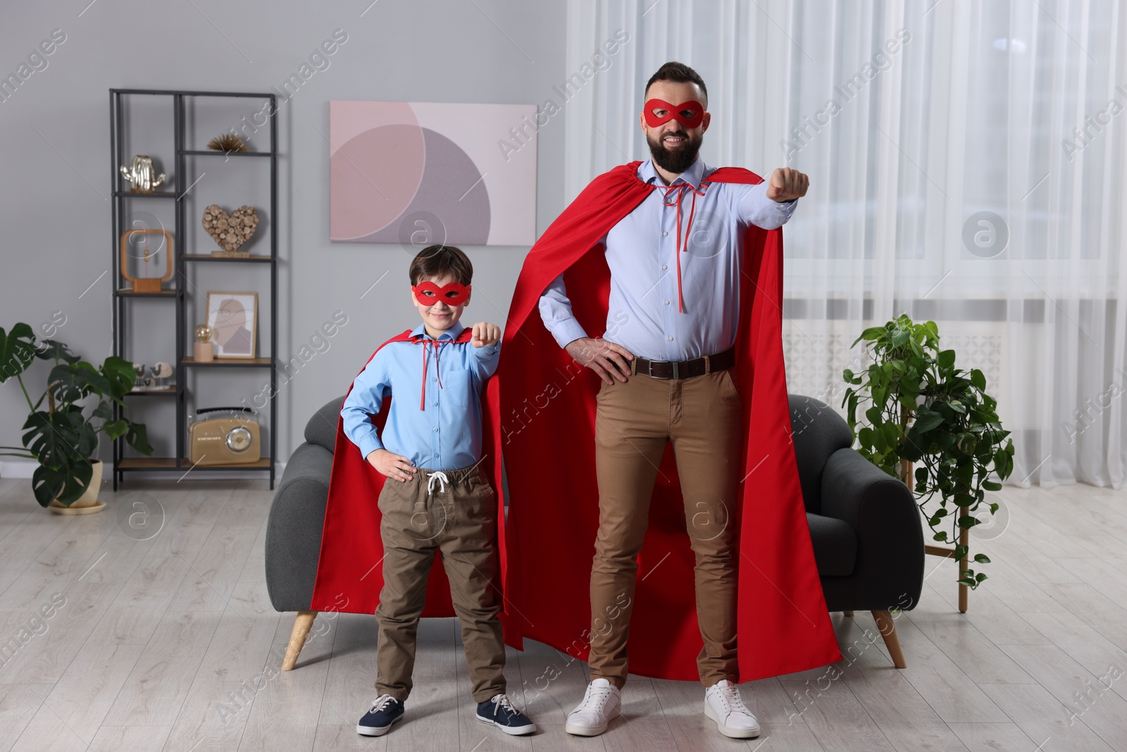 Photo of Father and his son wearing superhero costumes at home