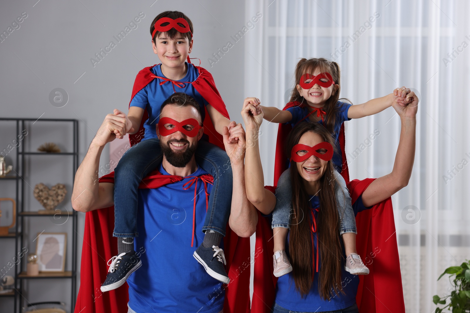 Photo of Parents and their children wearing superhero costumes at home