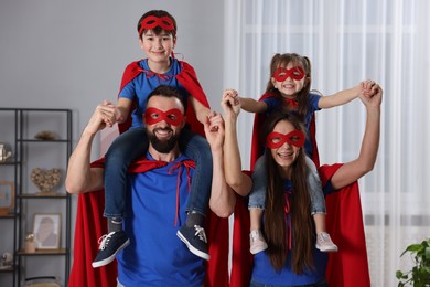 Photo of Parents and their children wearing superhero costumes at home