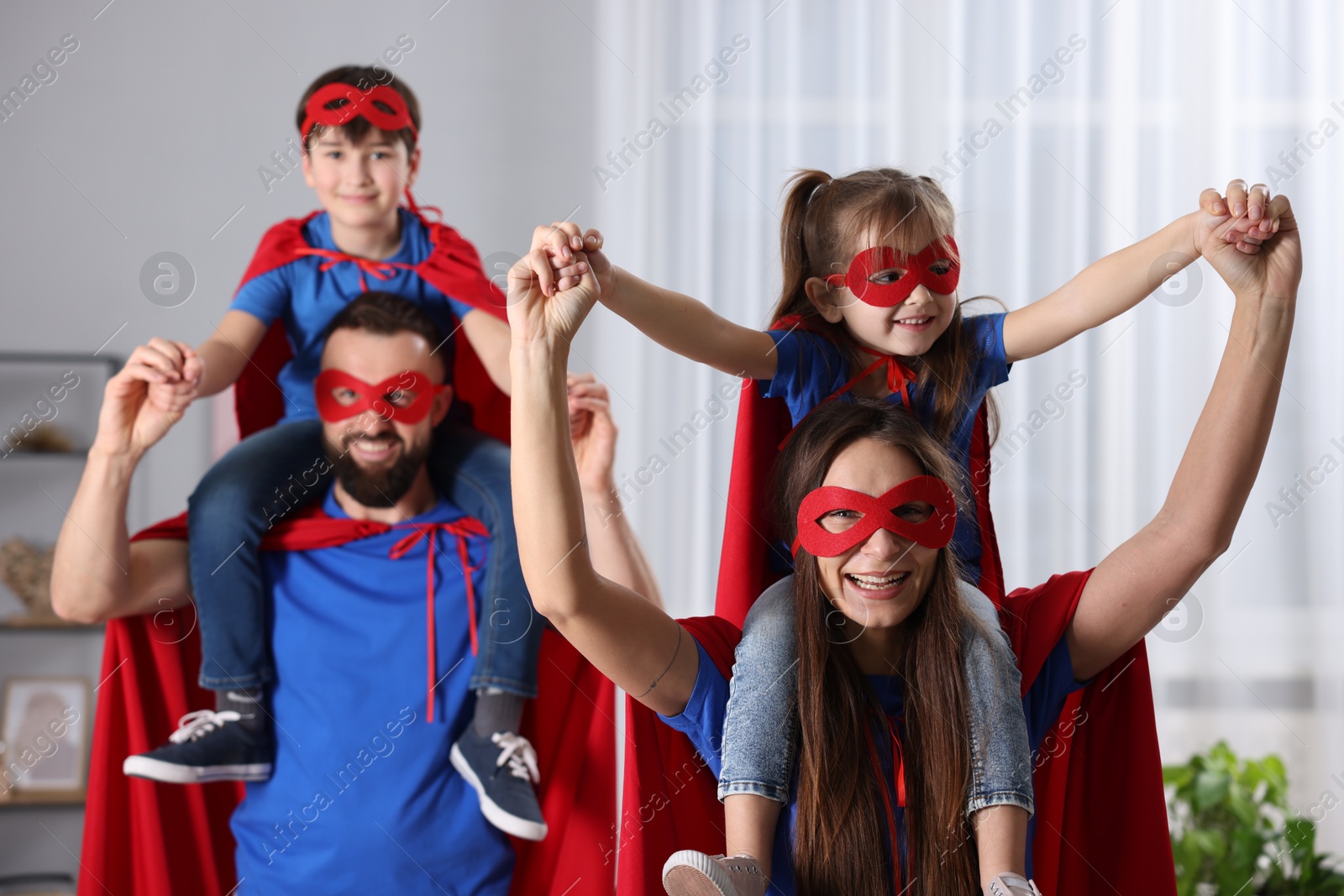 Photo of Parents and their children wearing superhero costumes at home