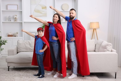 Photo of Parents and their son wearing superhero costumes at home