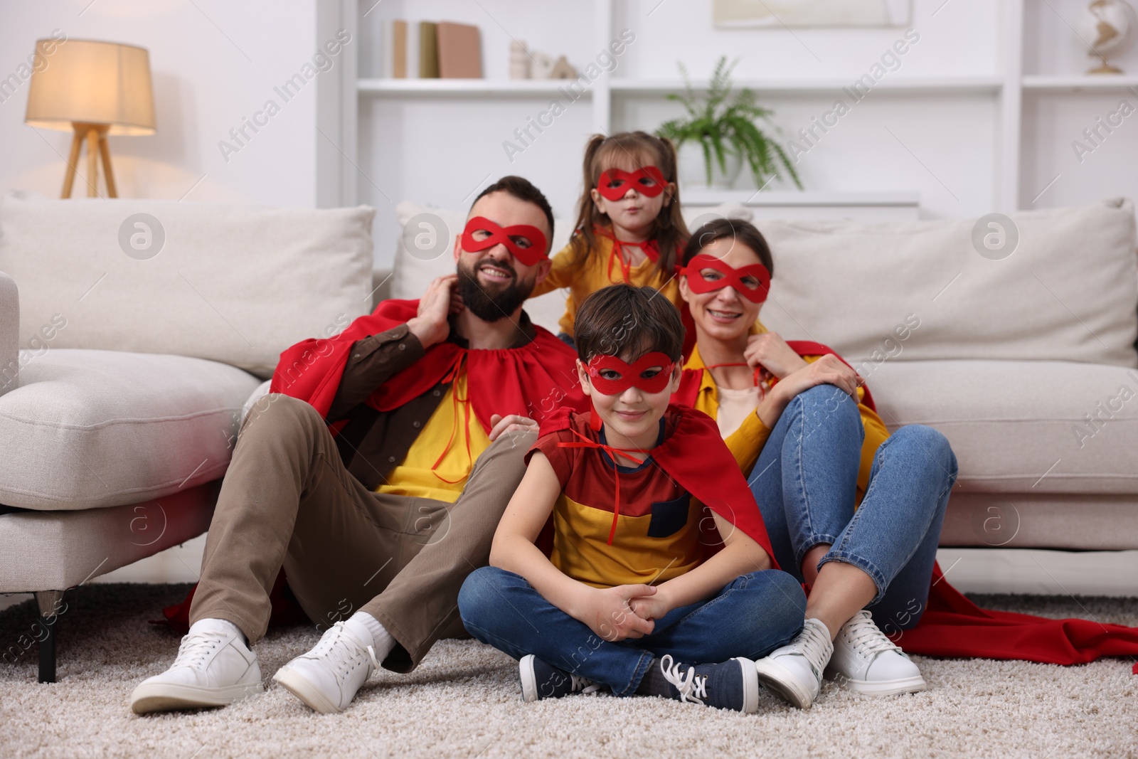 Photo of Parents and their children wearing superhero costumes at home