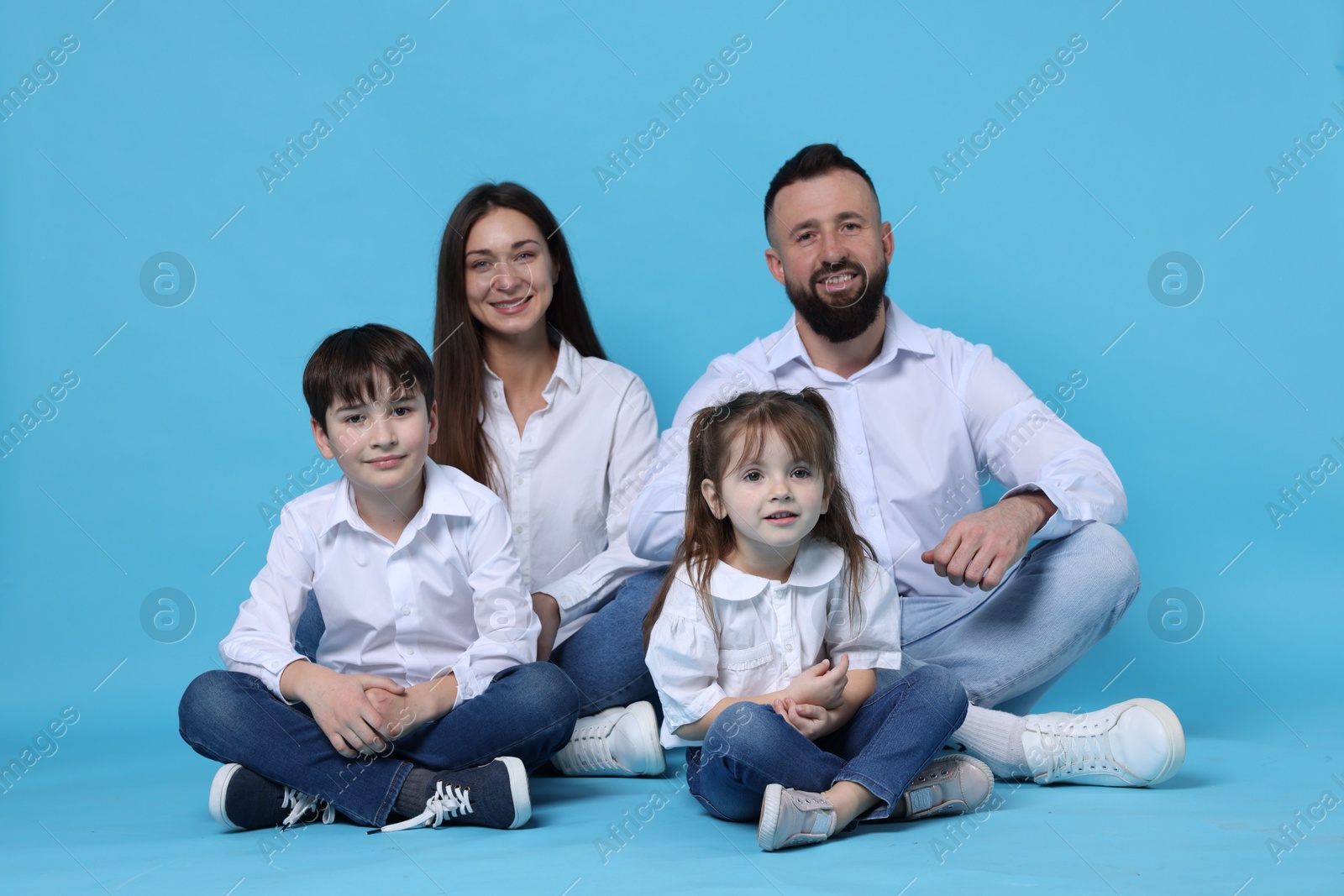 Photo of Happy parents and their children on light blue background