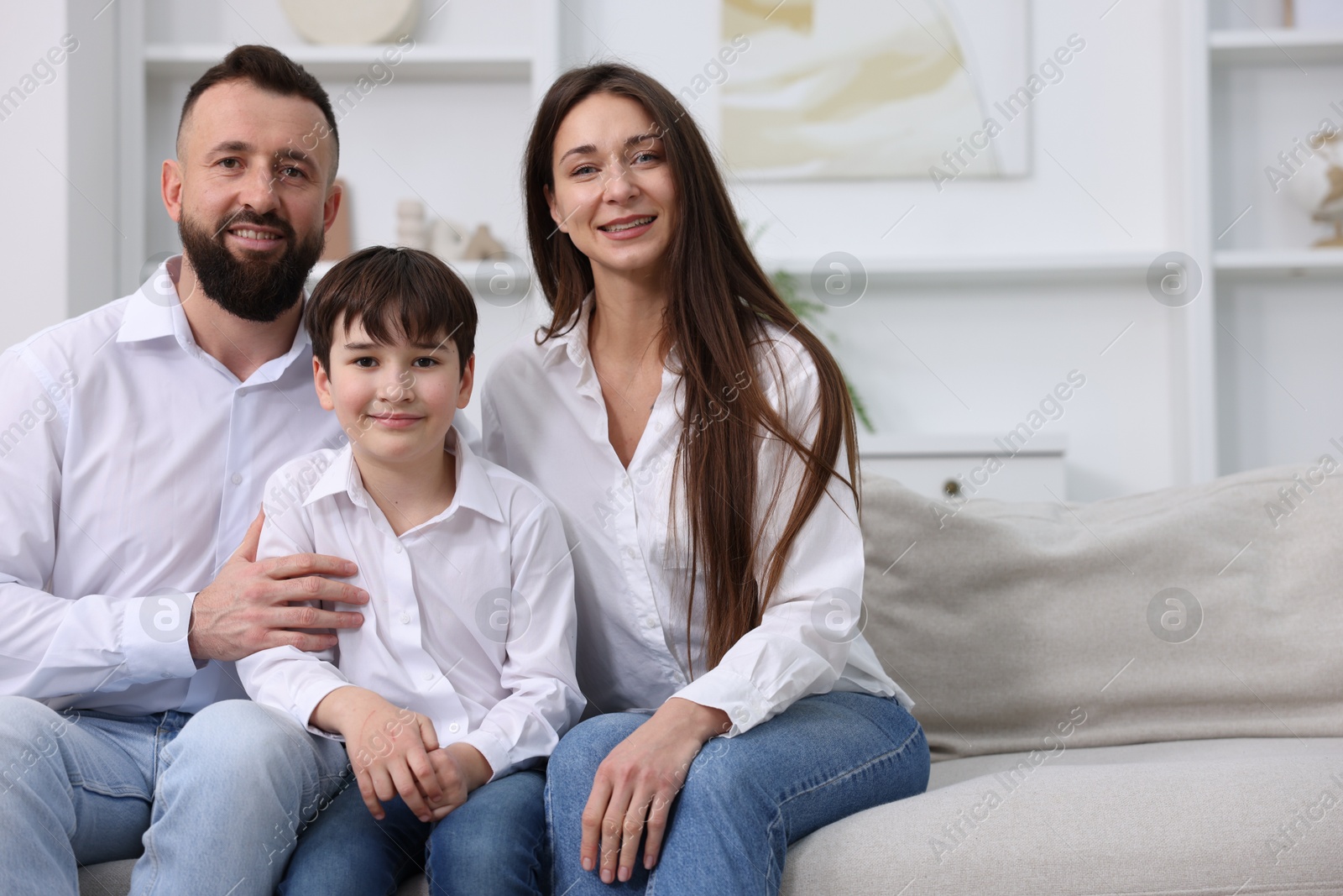 Photo of Happy parents and their son on sofa at home, space for text