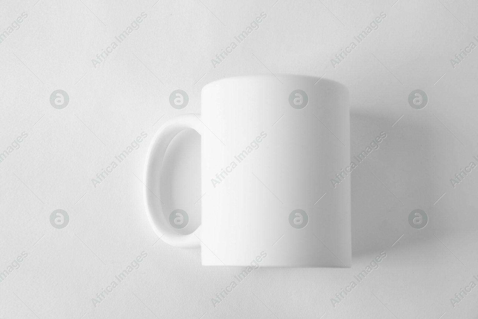 Photo of One blank mug on white background, top view. Mockup for design