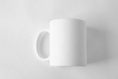 Photo of One blank mug on white background, top view. Mockup for design