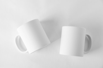 Photo of Two blank mugs on white background, top view. Mockup for design