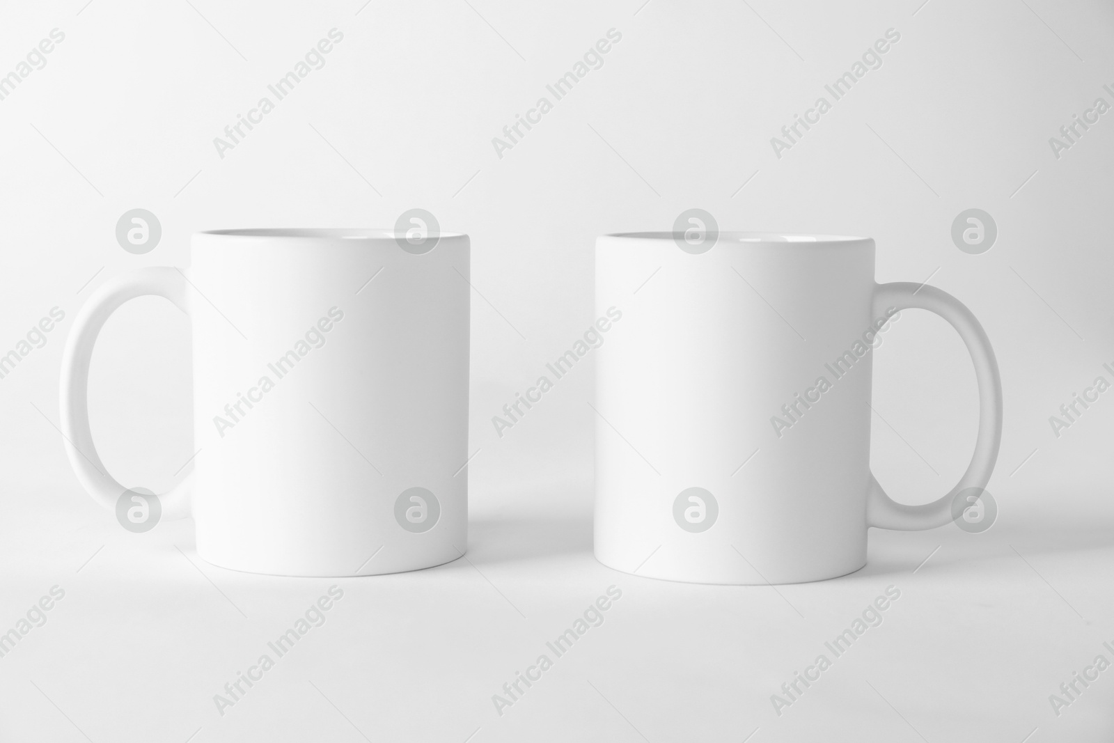 Photo of Two blank mugs on white background. Mockup for design