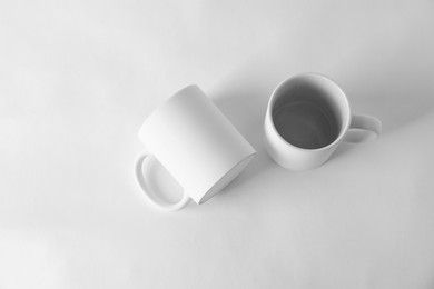 Photo of Two blank mugs on white background, top view. Mockup for design