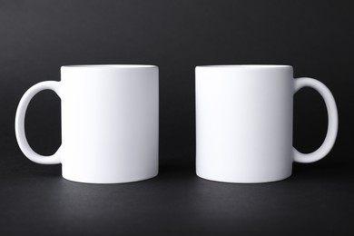 Two blank white mugs on black background. Mockup for design