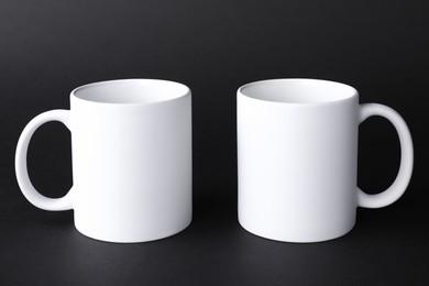 Two blank white mugs on black background. Mockup for design