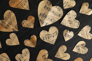 Photo of Paper hearts with notes on black table, flat lay