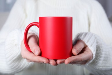 Photo of Woman holding blank red ceramic mug, closeup. Mockup for design