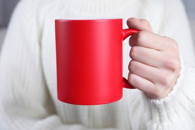 Photo of Woman holding blank red ceramic mug, closeup. Mockup for design