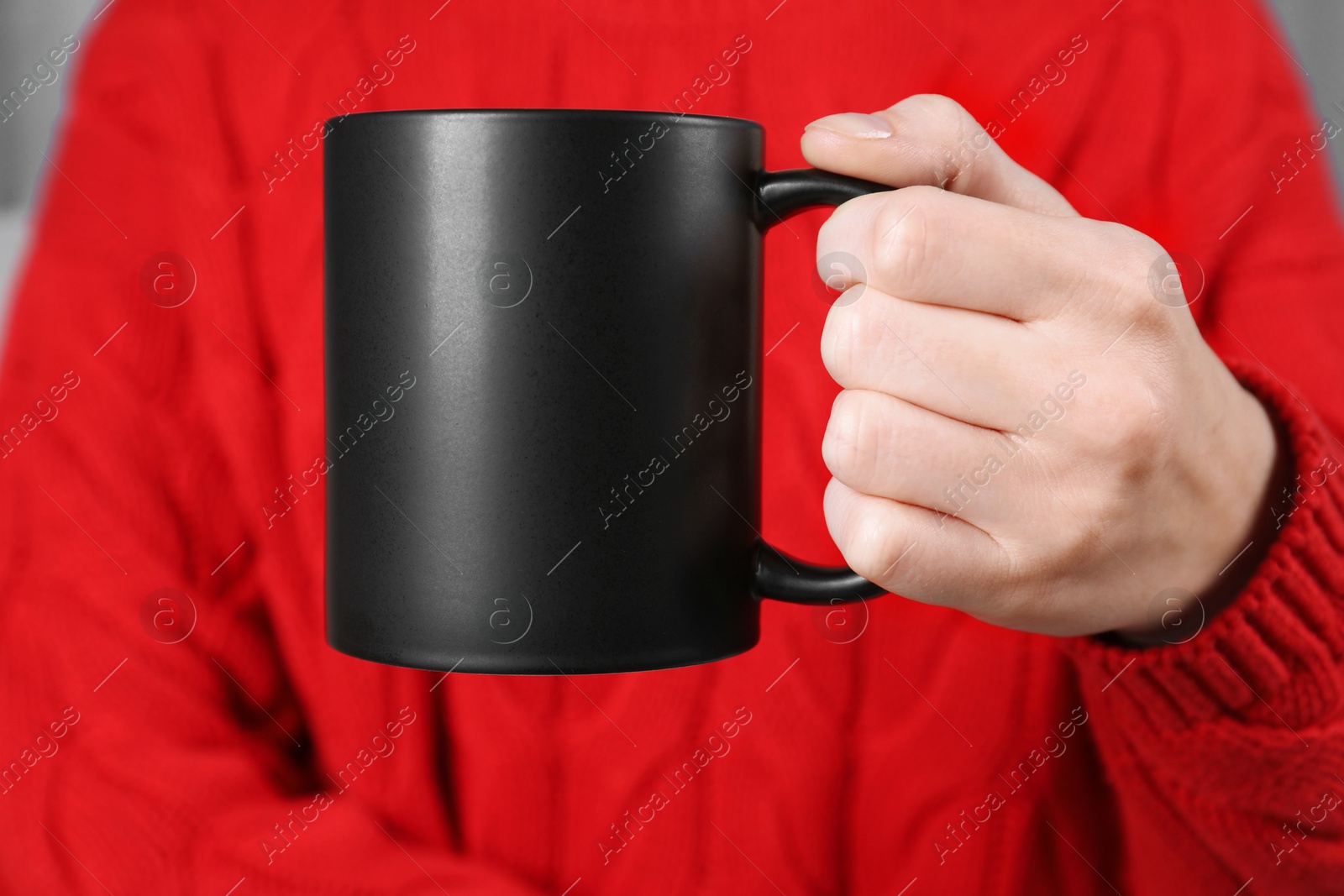 Photo of Woman holding blank black ceramic mug, closeup. Mockup for design