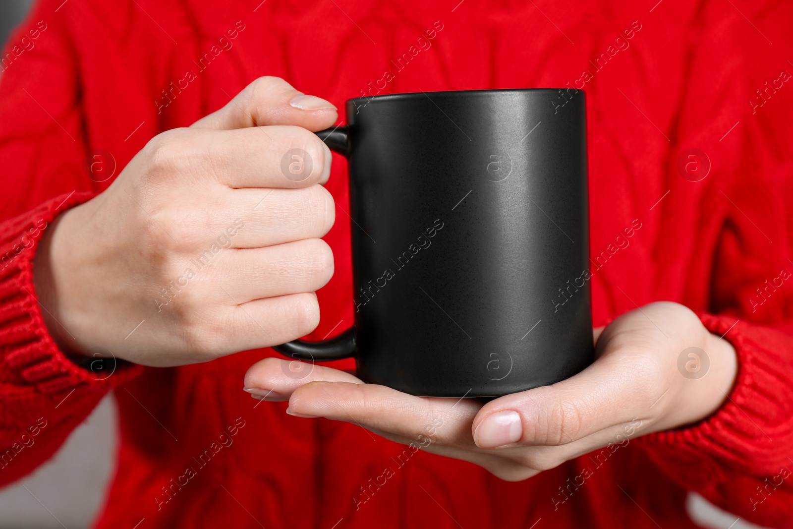 Photo of Woman holding blank black ceramic mug, closeup. Mockup for design