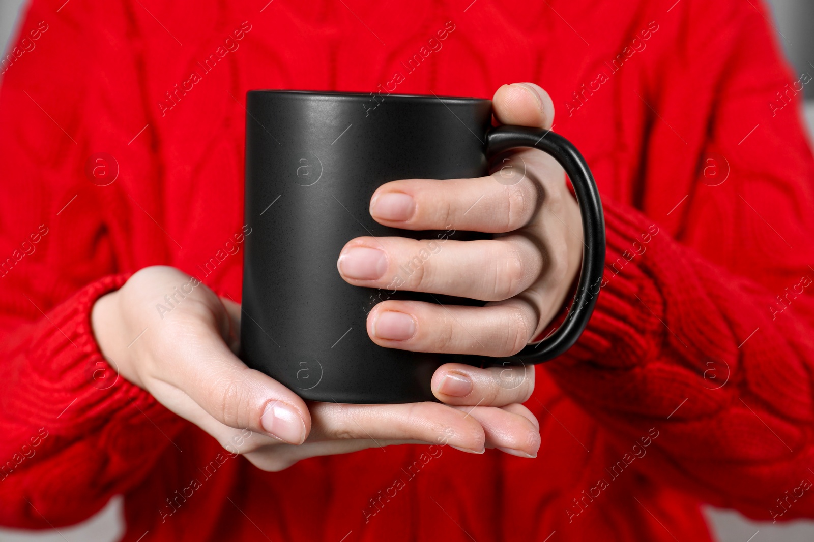 Photo of Woman holding blank black ceramic mug, closeup. Mockup for design