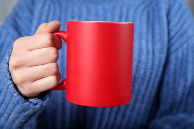 Photo of Woman holding blank red ceramic mug, closeup. Mockup for design