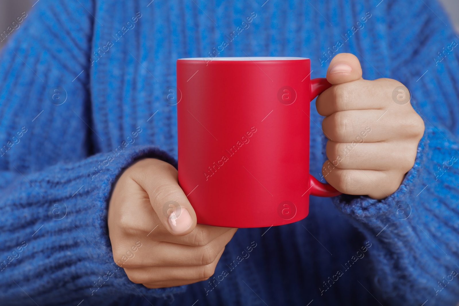 Photo of Woman holding blank red ceramic mug, closeup. Mockup for design