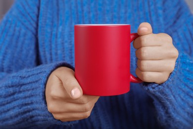 Photo of Woman holding blank red ceramic mug, closeup. Mockup for design