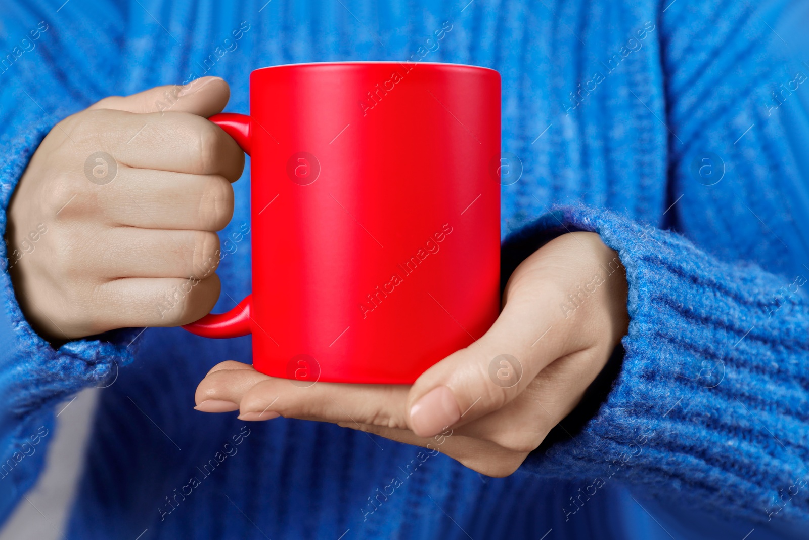 Photo of Woman holding blank red ceramic mug, closeup. Mockup for design