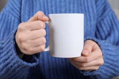 Photo of Woman holding blank white ceramic mug, closeup. Mockup for design