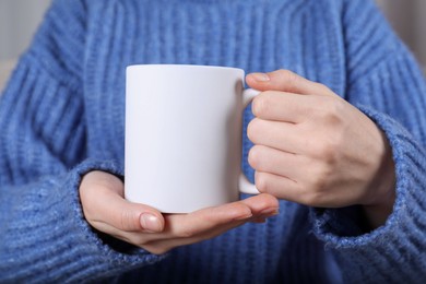 Photo of Woman holding blank white ceramic mug, closeup. Mockup for design