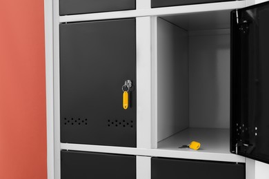 Modern lockers with keys on coral background, closeup