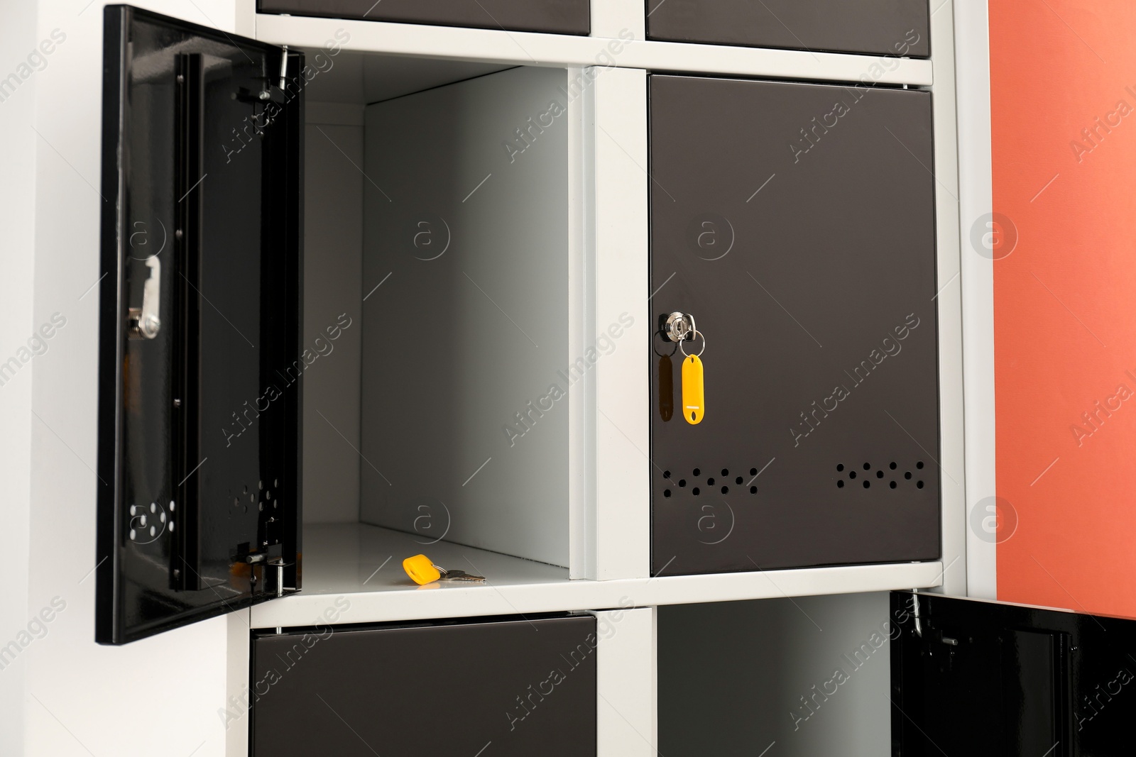 Photo of Modern lockers with keys on coral background, closeup