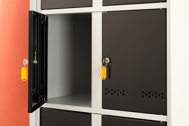 Photo of Modern lockers with keys on coral background, closeup