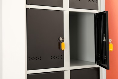 Modern lockers with keys on coral background, closeup