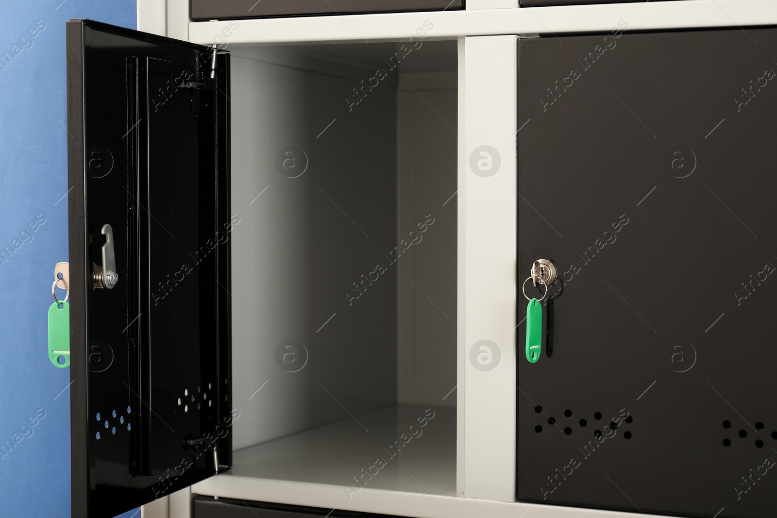 Photo of Modern lockers with keys on blue background, closeup