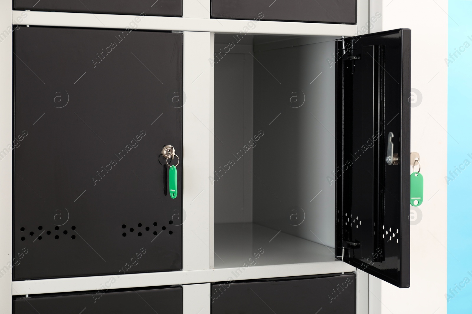 Photo of Modern lockers with keys on light blue background, closeup