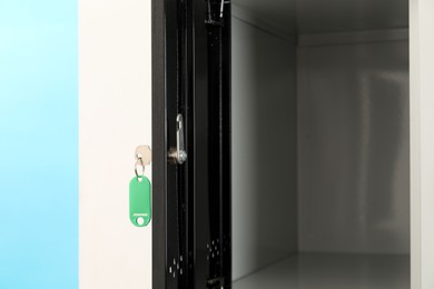 Photo of Open locker with key on light blue background, closeup