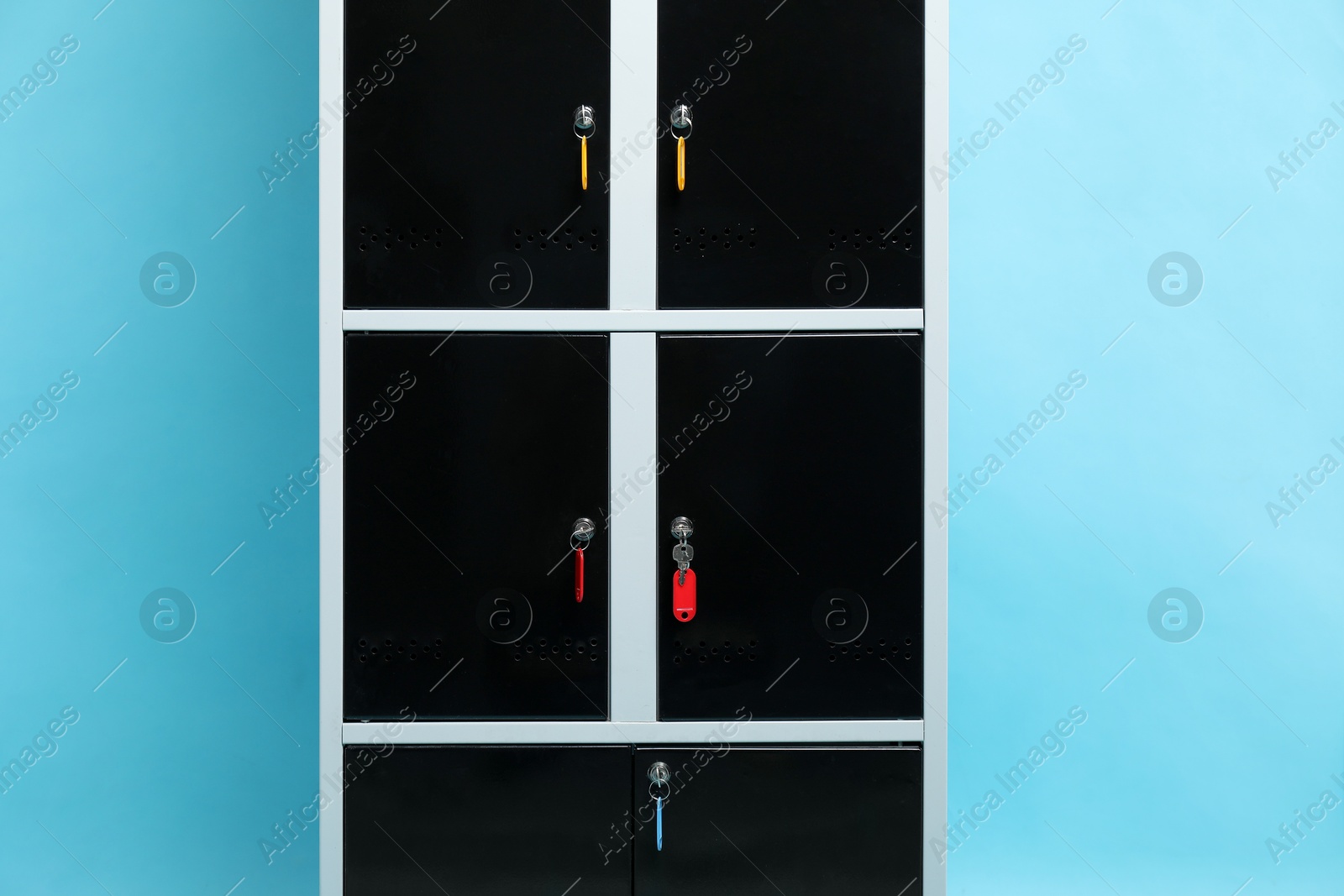 Photo of Modern lockers with keys on light blue background