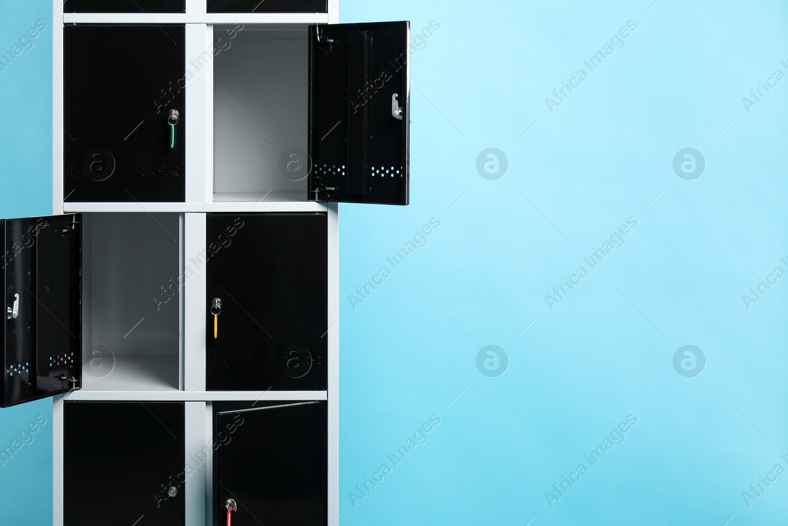 Photo of Modern lockers with keys on light blue background, space for text