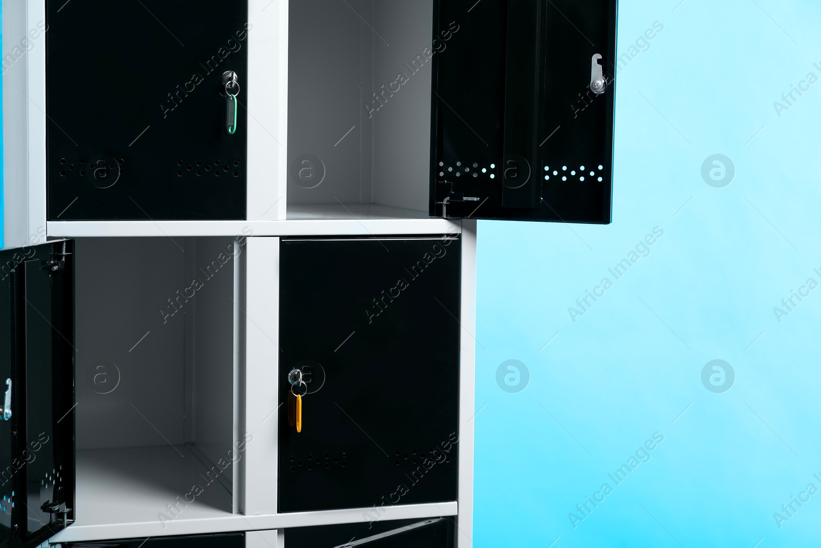 Photo of Modern lockers with keys on light blue background, space for text