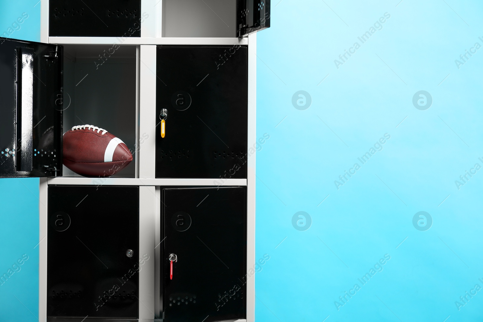 Photo of Open locker with american football ball on light blue background, space for text