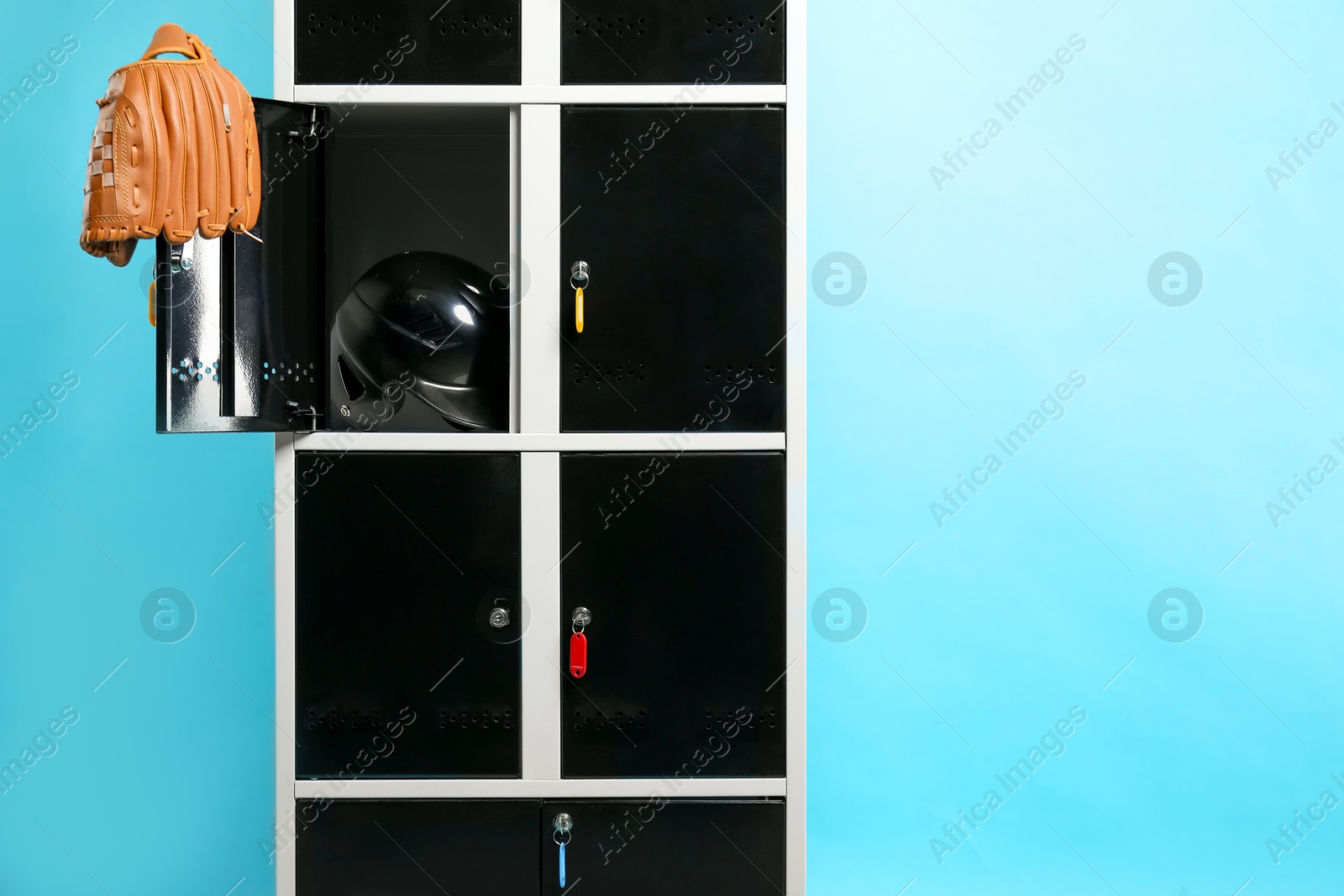 Photo of Open locker with baseball glove and helmet on light blue background, space for text