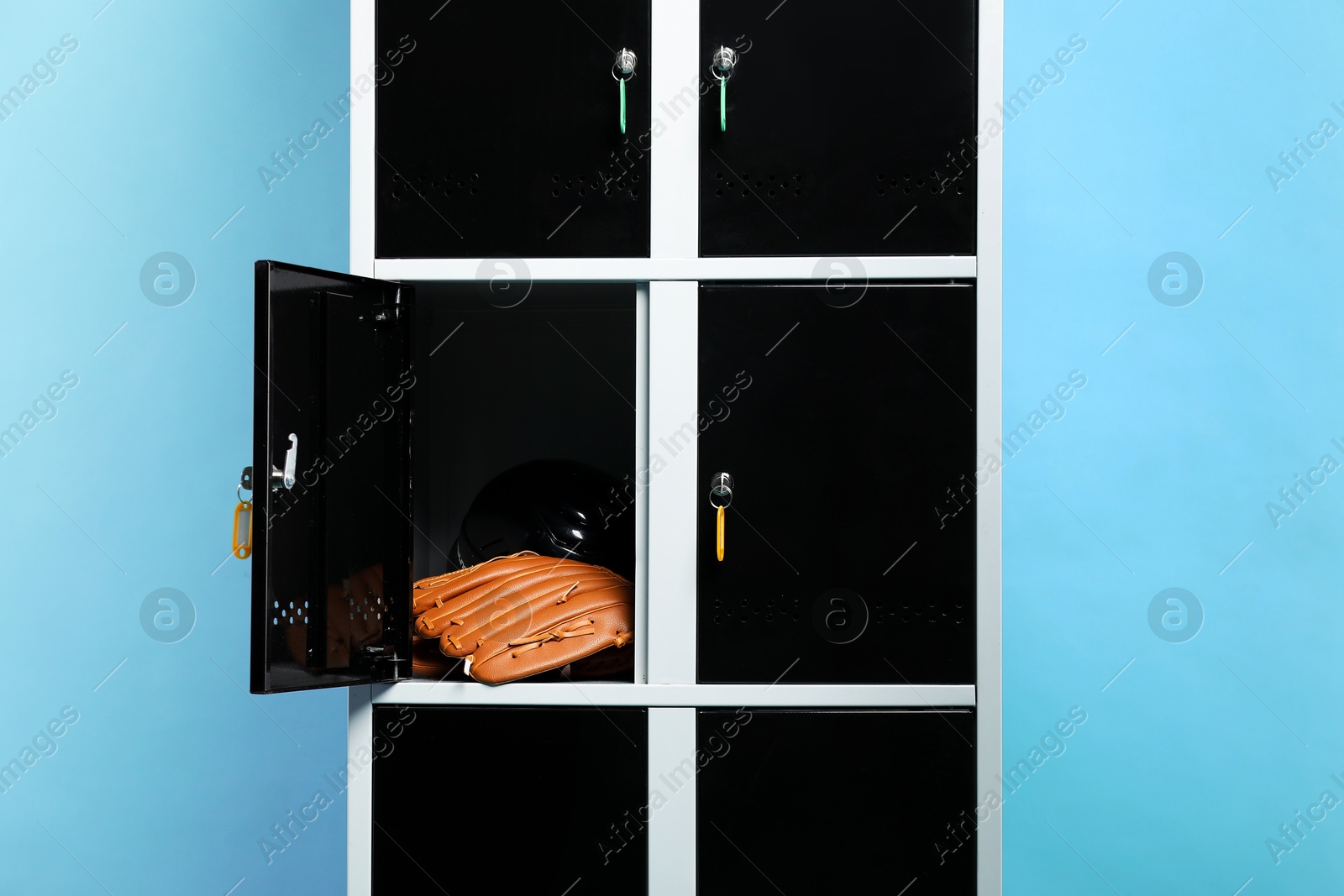 Photo of Open locker with baseball glove and helmet on light blue background